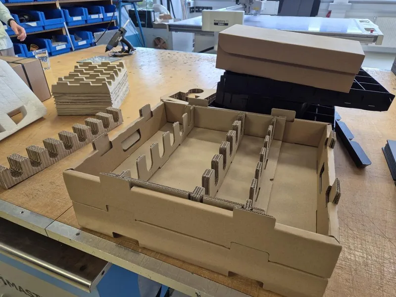 Corrugated cardboard trays with notched dividers and inserts on a workshop table