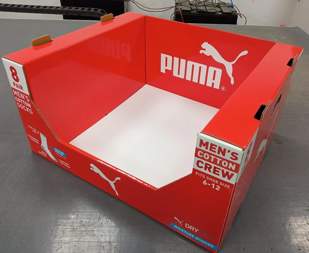 Red corrugated retail display bin with printed graphics for a men's cotton socks pack, shown as a finished sample