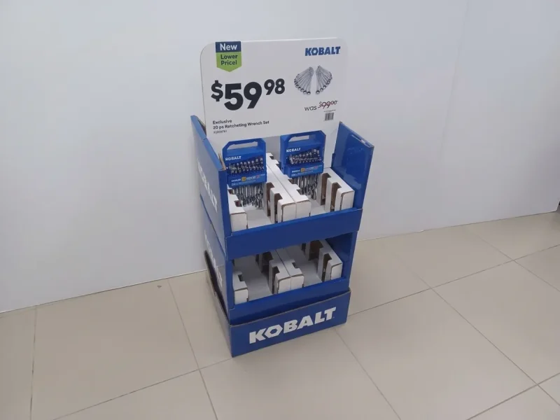 Printed mockup of a blue and white corrugated floor display with a price header, holding boxed wrench sets on divided trays